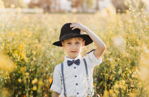Een kleine jongen met een hoed op een koolzaadveld. Landelijk landschap