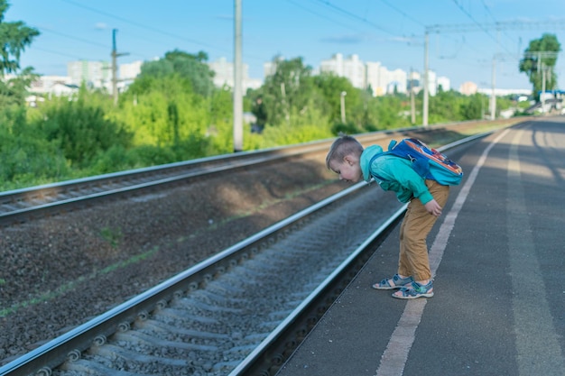Een kleine jongen met een rugzak wacht op de trein Een kind staat alleen op het perron in afwachting van een elektrische trein