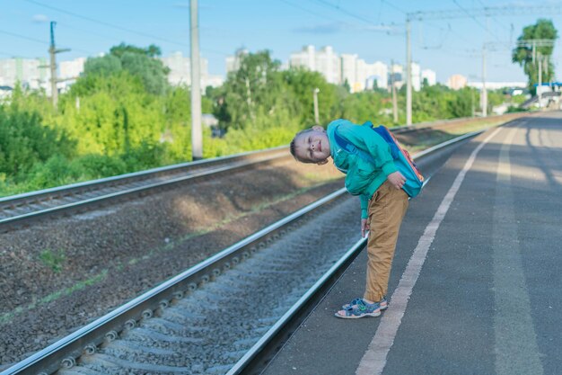 Een kleine jongen met een rugzak wacht op de trein Een kind staat alleen op het perron in afwachting van een elektrische trein