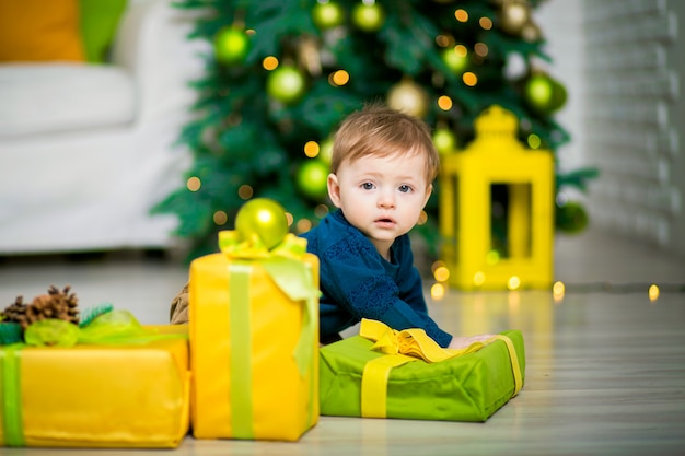 Een kleine jongen onder de kerstboom ligt, naast zijn kerstcadeau dozen.