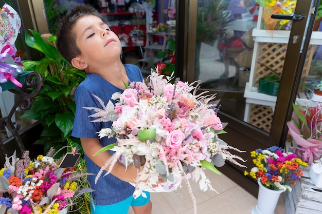 Een kleine jongen pakt een bos bloemen op en houdt hem voor