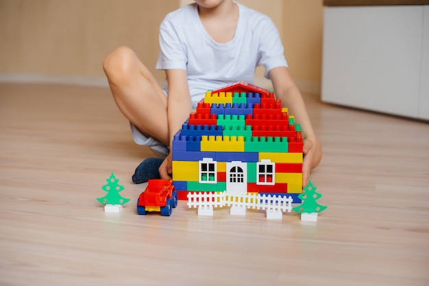 Een kleine jongen speelt met een bouwpakket en bouwt een groot huis voor het hele gezin. Bouw van een gezinswoning.