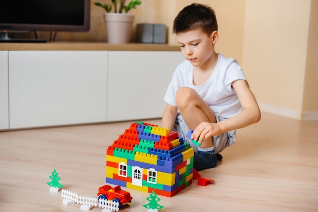 Een kleine jongen speelt met een bouwpakket en bouwt een groot huis voor het hele gezin. Bouw van een gezinswoning.