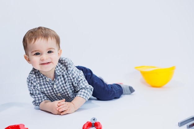 Een kleine jongen speelt met een set bouwgereedschap op een witte achtergrond Plastic kinderspeelgoed