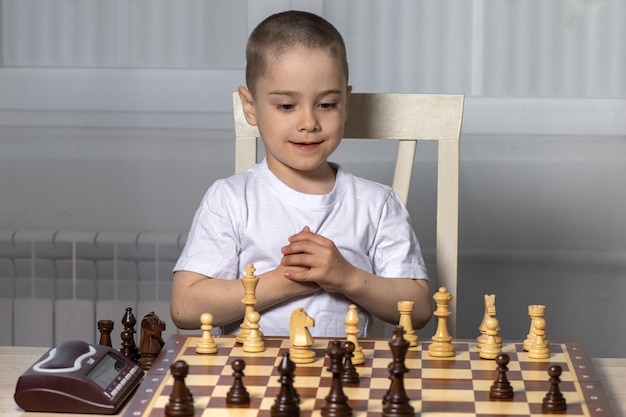 Een kleine jongen speelt schaak, hij is erg blij en houdt van deze activiteit