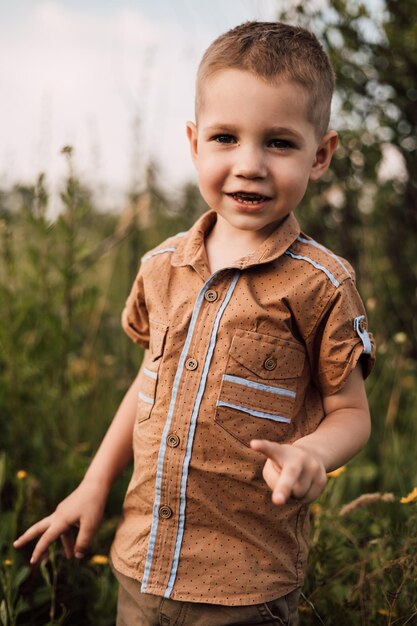 Een kleine jongen staat in de natuur en lacht