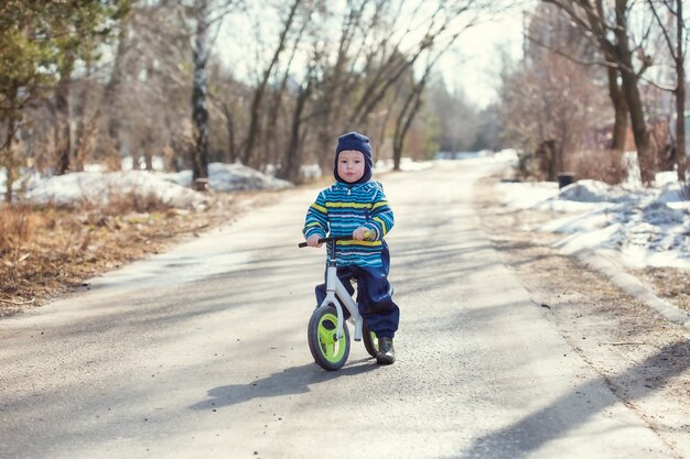 Een kleine jongen van 2 jaar leert op de weg in het dorp op een loopfiets te rijden