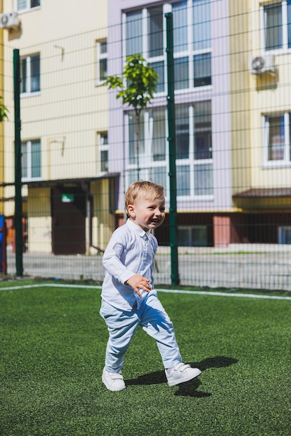Een kleine jongen van 2 jaar oud in een shirt en broek rent en lacht Een kind op een zonnige dag verheugt zich en lacht