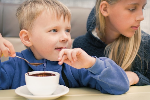 Een kleine jongen van 35 jaar eet warme chocolademelk in een café-restaurant