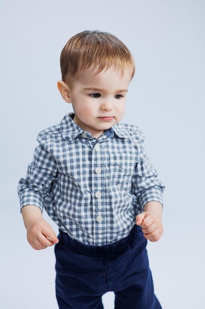 Een kleine jongen van een jaar oud op een witte achtergrond in een geruit hemd Een klein kind met een glimlach op zijn gezicht