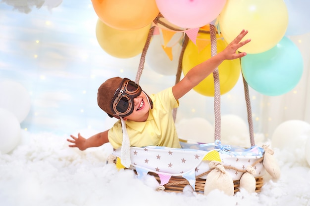 Een kleine jongen zit in een ballonmand in de wolken