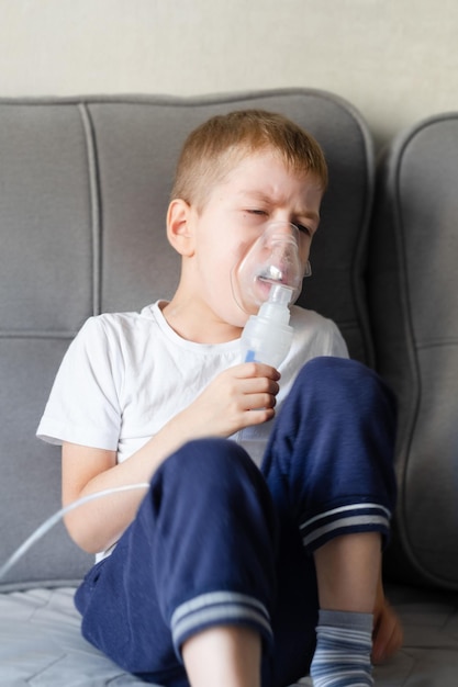 Een kleine jongen zit met een inhalatiemasker tijdens hoest en bronchitis