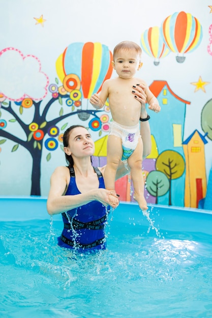 Een kleine jongen zwemt in het zwembad met een coach die kinderen leert zwemmen.