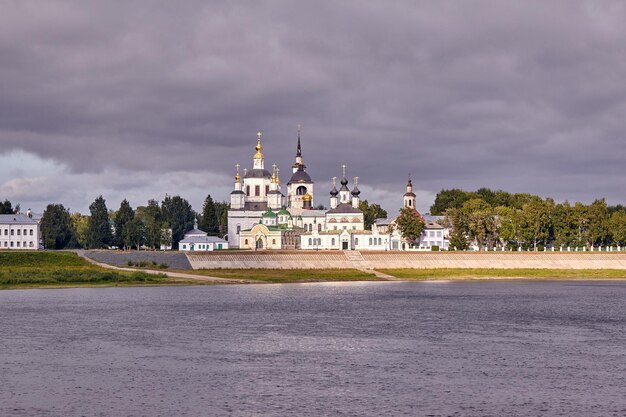 Een kleine kerk en de klokkentoren aan de oevers van de rivier, Rusland, het dorp