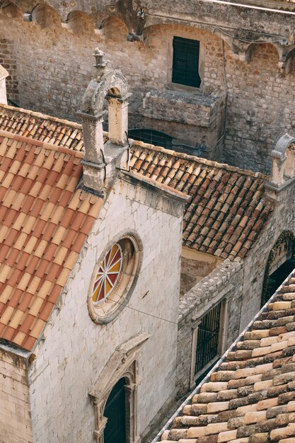 Een kleine kerk met een ronde glas-in-loodrozet en een pannendak in dubrovnik, kroatië