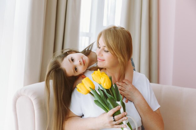 Een kleine kleindochter geeft haar oma een boeket tulpen Een gelukkig gezin Het concept van dankbaarheid houdt van welzijn