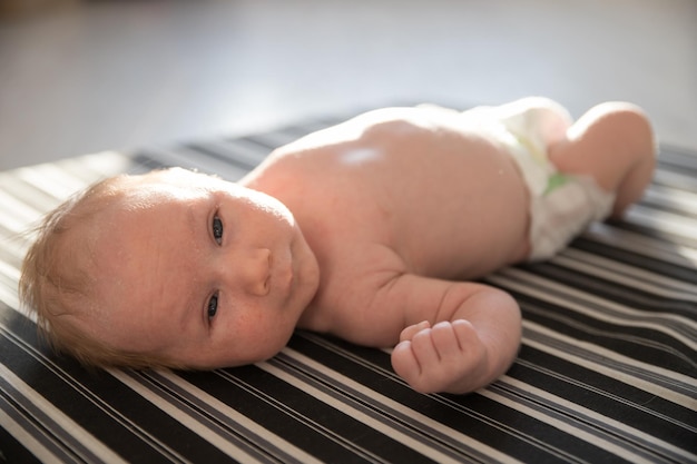 Een kleine pasgeboren baby in een luier die op zijn rug ligt