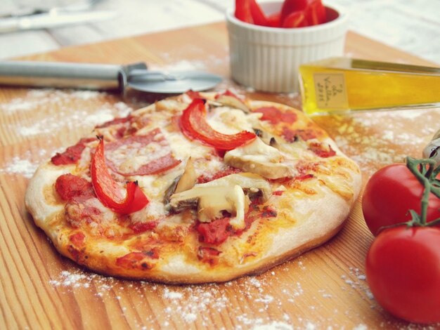 Een kleine pizza met champignons en champignons op een houten ondergrond.