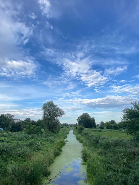 Foto een kleine rivier met een langzaam stromend landschap met een prachtige blauwe lucht