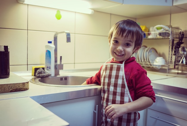 Een kleine schattige jongen afwas