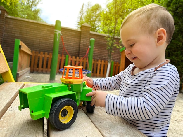 Een kleine schattige jongen van anderhalf jaar speelt met speelgoedauto op de speelplaats Schattige peuter speelt met auto's en speelgoed buiten Familie vakantie kinderen levensstijl concept Selectieve aandacht