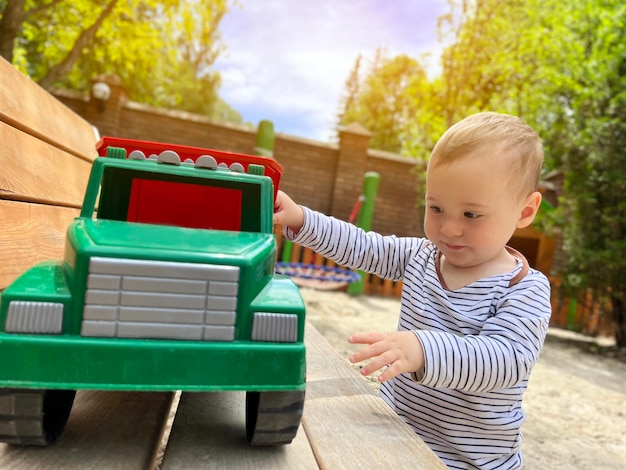 Een kleine schattige jongen van anderhalf jaar speelt met speelgoedauto op de speelplaats schattige peuter speelt met auto's en speelgoed buiten familie vakantie kinderen levensstijl concept selectieve aandacht