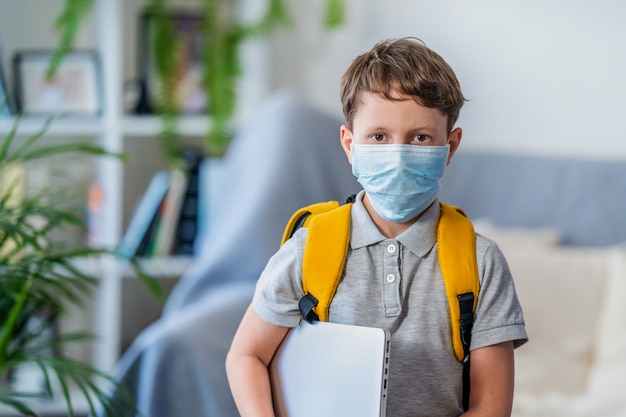 Een kleine schooljongen draagt een masker, bescherming tijdens het kroonvirus en griep.