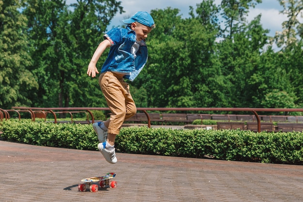 Een kleine stadsjongen en een skateboard. Een jonge man rijdt in een park op een skateboard