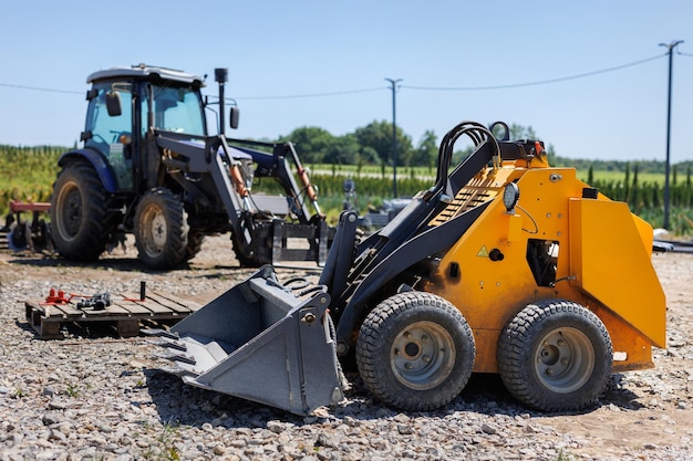 Foto een kleine tractor met een emmer voor het verplaatsen van gras en bulkmateriaal