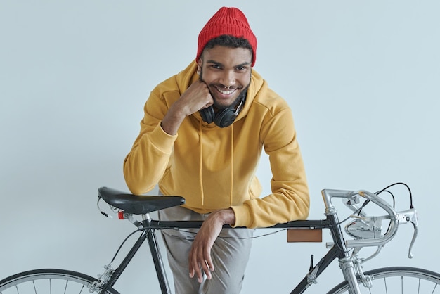 Foto een knappe afrikaanse man leunt op zijn fiets en glimlacht terwijl hij tegen de muur staat.