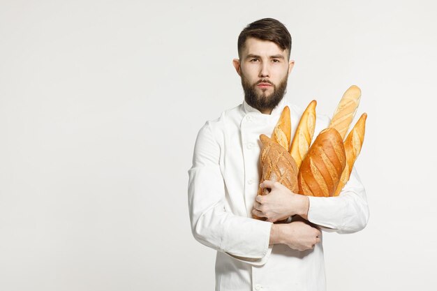 Een knappe bakker in uniform houdt baguettes op een witte achtergrond bakkerij reclame concept