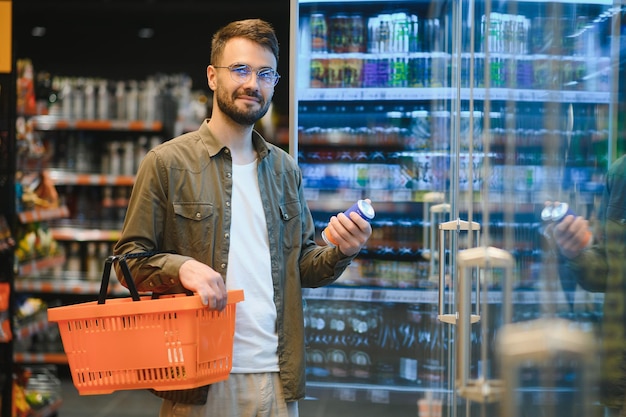 Een knappe jonge man die eten kiest in de supermarkt.