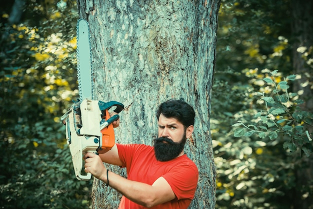 Een knappe jonge man met een baard draagt een boom ontbossing is een belangrijke oorzaak van landdegradatie
