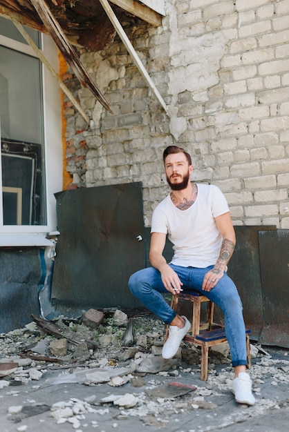 Een knappe jonge man met een baard in een interieur in grunge-stijl