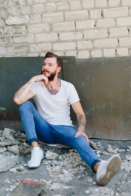 Een knappe jonge man met een baard in een interieur in grunge-stijl