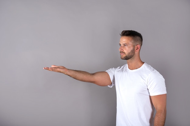 Een knappe jongeman in een wit t-shirt die iets met zijn handpalmen laat zien