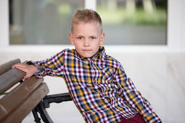 Foto een knappe jongen met europees uiterlijk zit op een bankje en kijkt naar de camera