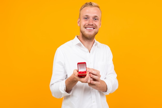 Een knappe man houdt een ring vast en doet een aanbod, portret osolated op geel