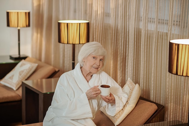 Een knappe oude dame in een wit gewaad in een hotelkamer