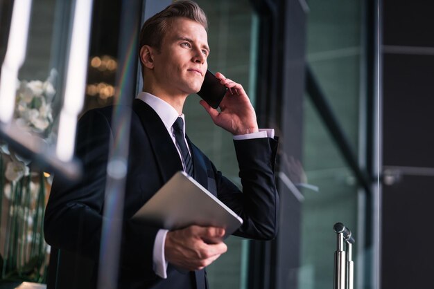 Een knappe zakenman die op kantoor aan de telefoon luistert.