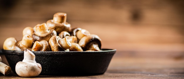 Een koekenpan met gebakken champignons op tafel