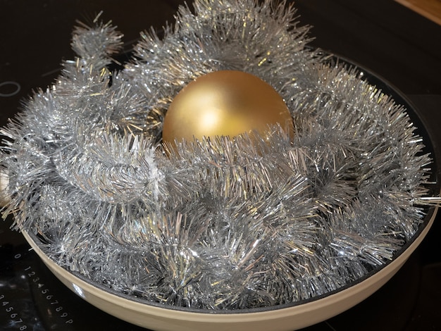 Een koekenpan vol kerstklatergoud en een gouden bol in het midden. Concept van voorbereiding op het nieuwe jaar en Kerstmis.