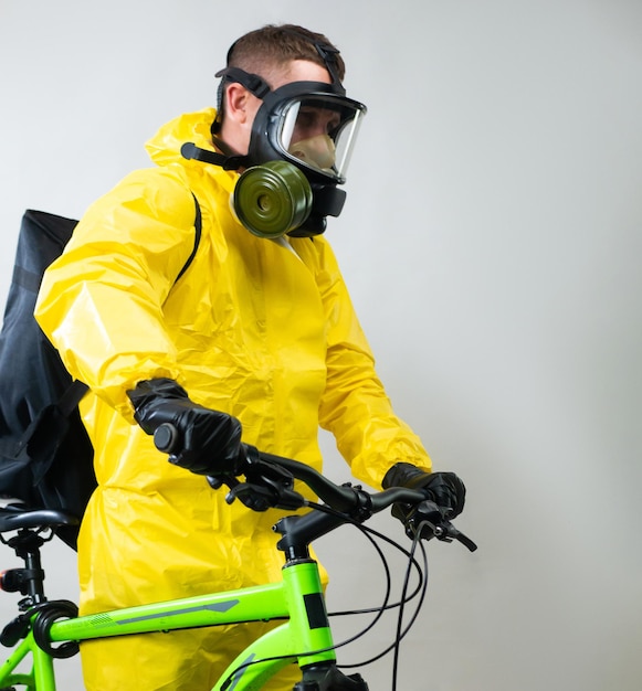 Een koerier die eten bezorgt op een fiets met een gasmasker en een geel beschermend pak