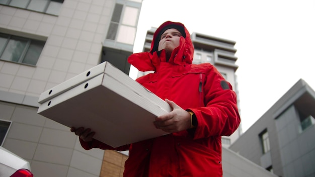 Een koerier in rode kleren die pizzadozen vasthoudt