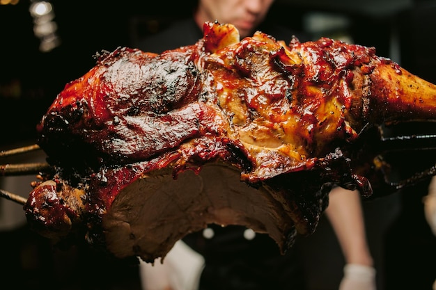 Een kok in een restaurant bereidt aan het spit een smakelijk geroosterd lamsvlees met een krokant korstje.Vlees in brand.