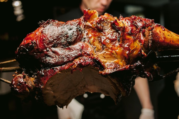 Een kok in een restaurant bereidt aan het spit een smakelijk geroosterd lamsvlees met een krokant korstje.vlees in brand.