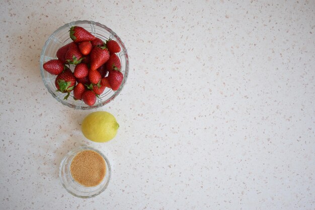 Een kom aardbeien een citroen en bruine suiker De ingrediënten van een limonade