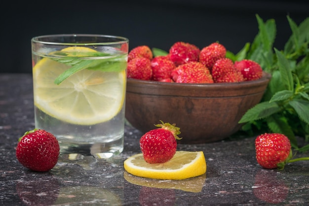 Een kom aardbeienwater met citroen en munt op een stenen tafel