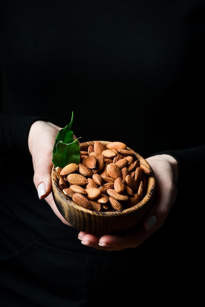 Een kom amandelen in vrouwelijke handen Gezond, calorierijk veganistisch voedselconcept Close-up