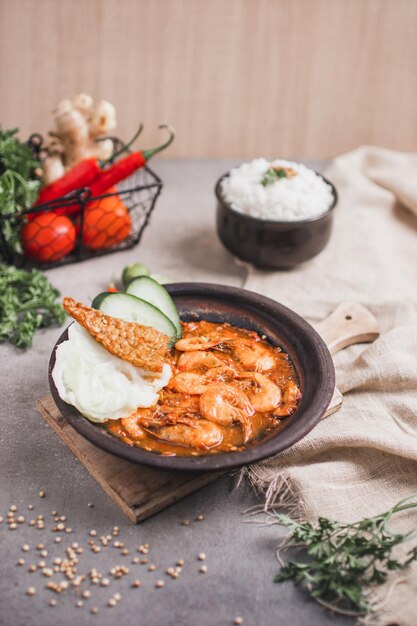 Foto een kom garnalencurry met rijst en groenten op tafel.